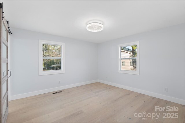 1315 Vickie Ln, Matthews, NC 28104 - empty room with a barn door, healthy amount of natural light, and light wood finished floors