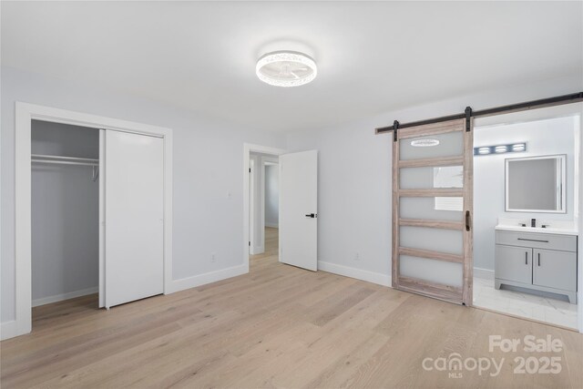1315 Vickie Ln, Matthews, NC 28104 - unfurnished bedroom with light wood-type flooring, a barn door, a closet, and ensuite bath