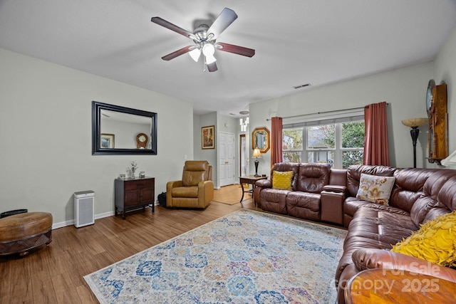 living area with wood finished floors, visible vents, baseboards, and ceiling fan