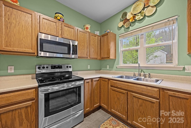 kitchen featuring light countertops, a sink, stainless steel appliances, and light tile patterned floors