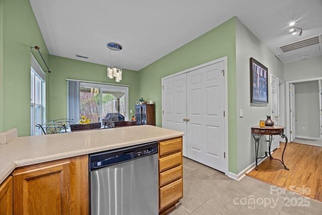 kitchen with light countertops, visible vents, brown cabinetry, and stainless steel dishwasher