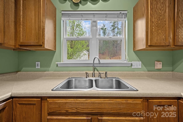 kitchen featuring light countertops, a sink, and brown cabinetry