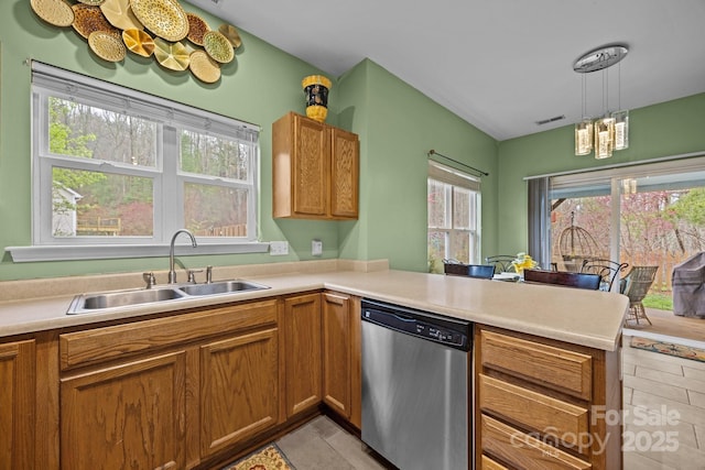 kitchen featuring visible vents, a peninsula, dishwasher, a sink, and brown cabinetry