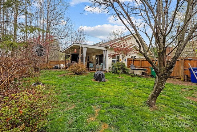 rear view of property featuring a fenced backyard and a yard