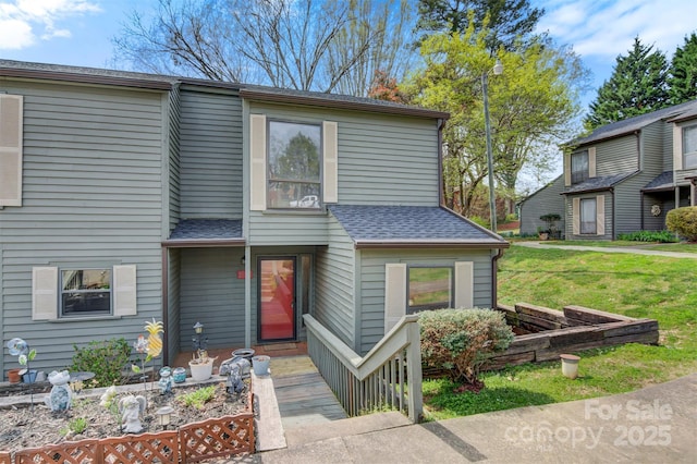 view of front of house with a shingled roof and a front lawn