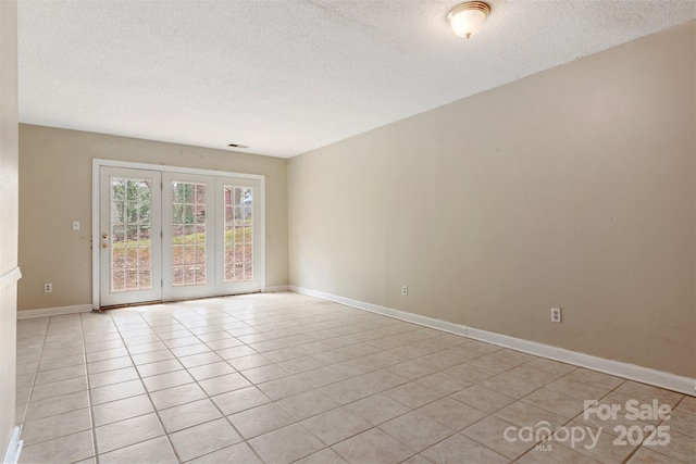 spare room with a textured ceiling, baseboards, and light tile patterned floors
