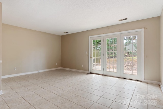 spare room with a textured ceiling, visible vents, baseboards, and light tile patterned flooring