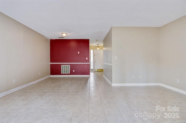 empty room with light tile patterned floors, visible vents, and baseboards