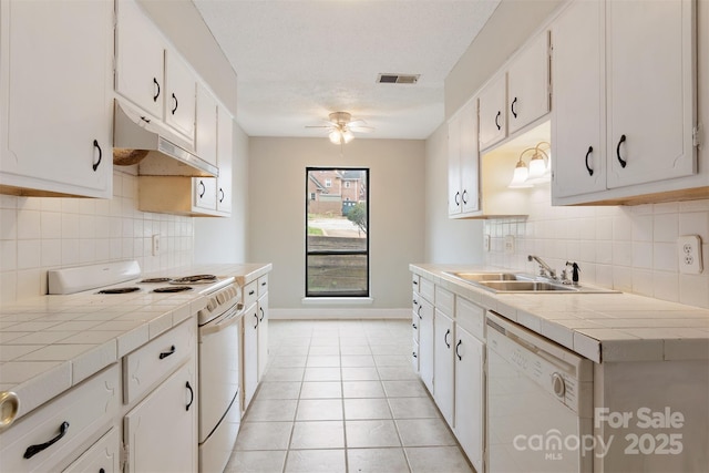 kitchen with tile counters, visible vents, ceiling fan, white appliances, and under cabinet range hood