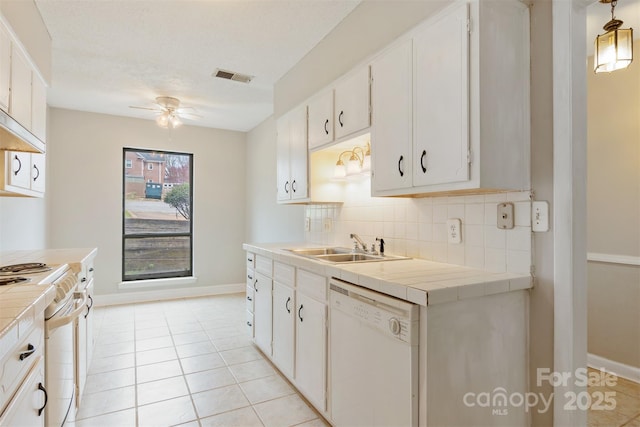 kitchen with stove, tile countertops, visible vents, and dishwasher