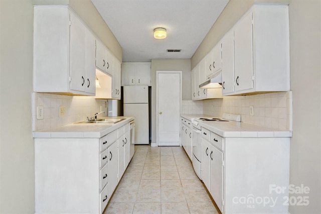 kitchen with backsplash, white appliances, light countertops, and white cabinets