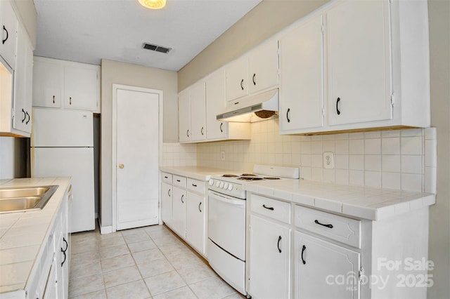 kitchen with under cabinet range hood, white appliances, and white cabinets