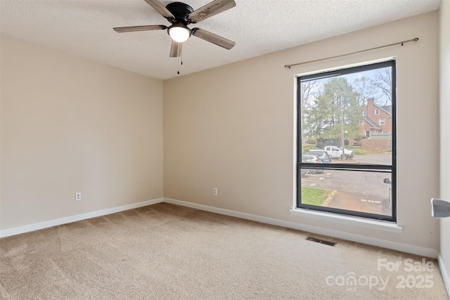 spare room with baseboards, a textured ceiling, visible vents, and carpet