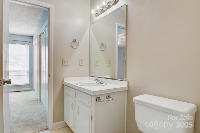 bathroom featuring vanity, a textured ceiling, baseboards, and toilet