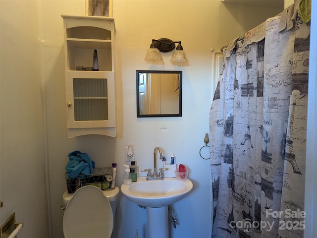 full bath featuring a sink, a shower with curtain, toilet, and visible vents