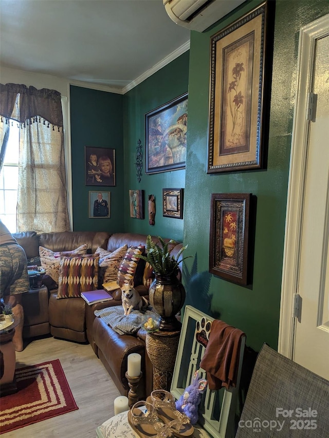living room with an AC wall unit, ornamental molding, and wood finished floors