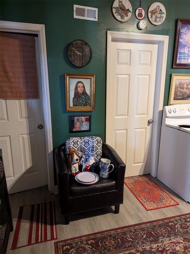 interior space with laundry area, washer / dryer, wood finished floors, and visible vents