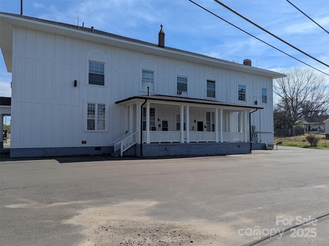 rear view of house with covered porch, crawl space, and a chimney