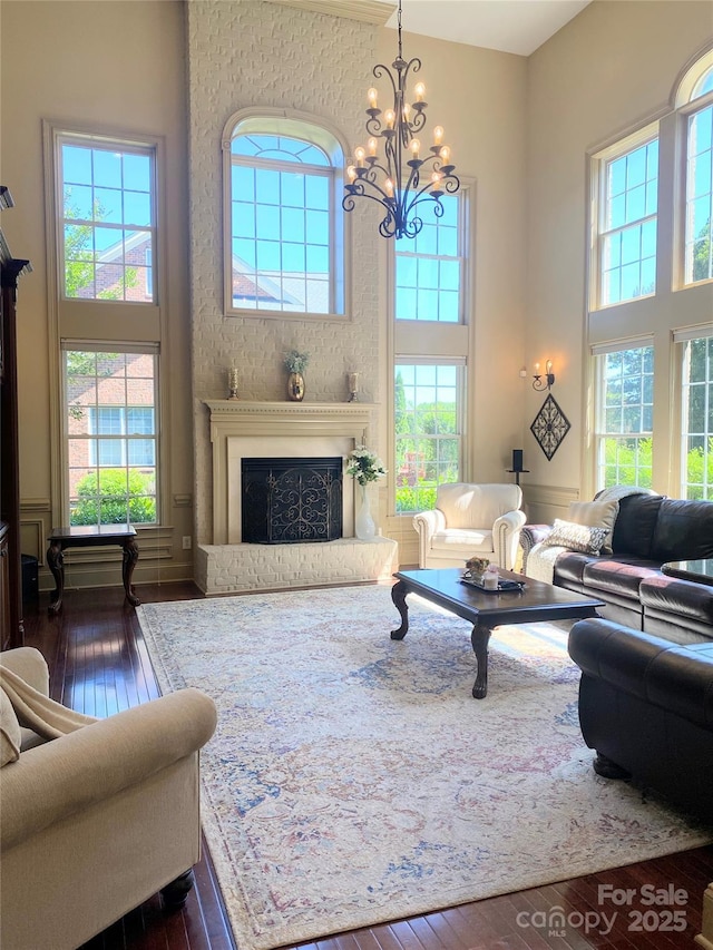 708 Ridgelake Dr, Weddington, NC 28104 - living area featuring a towering ceiling, dark wood-type flooring, healthy amount of natural light, a chandelier, and a fireplace with raised hearth