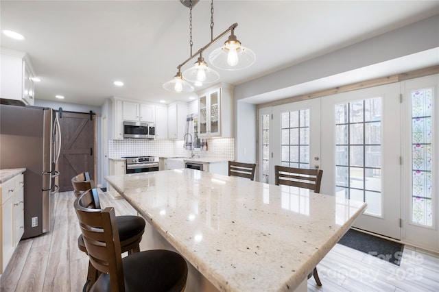 4487 Catawba Burris Rd, Denver, NC 28037 - kitchen featuring a kitchen breakfast bar, backsplash, a barn door, appliances with stainless steel finishes, and glass insert cabinets