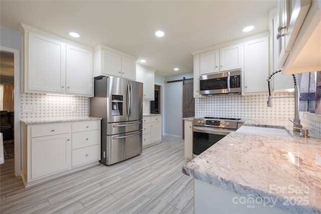 4487 Catawba Burris Rd, Denver, NC 28037 - kitchen with stainless steel appliances, a barn door, white cabinetry, a sink, and light stone counters