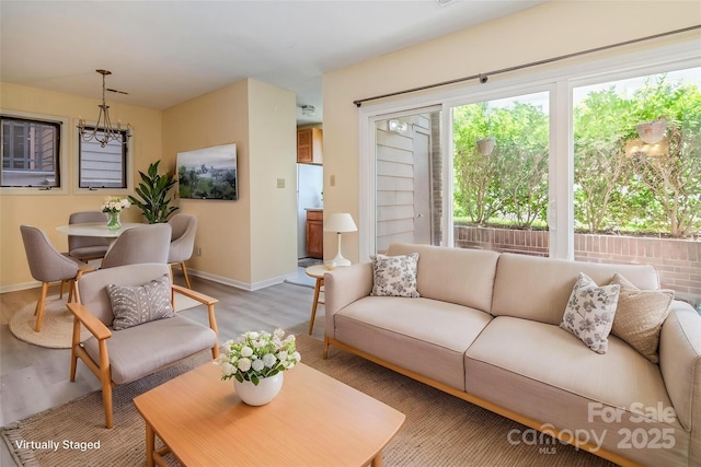 living area with baseboards, light wood finished floors, and a chandelier