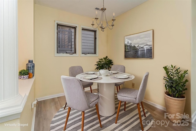 dining area with an inviting chandelier, baseboards, and wood finished floors