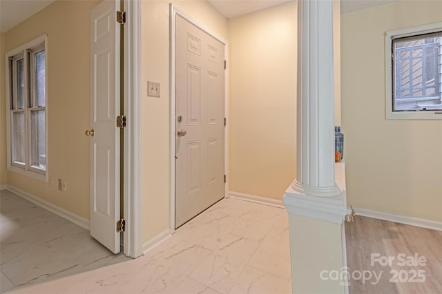 entrance foyer with baseboards, marble finish floor, and decorative columns