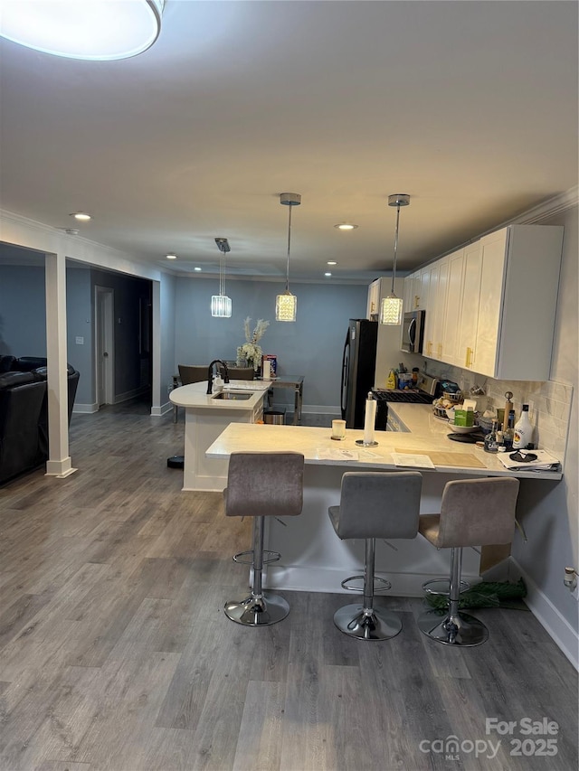 kitchen featuring a kitchen breakfast bar, light countertops, a sink, a peninsula, and stainless steel appliances