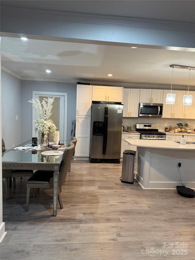 kitchen with recessed lighting, crown molding, appliances with stainless steel finishes, and light wood-type flooring