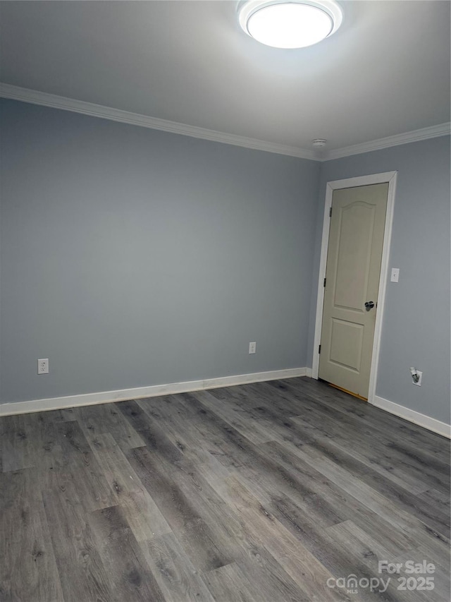 empty room featuring crown molding, baseboards, and dark wood finished floors