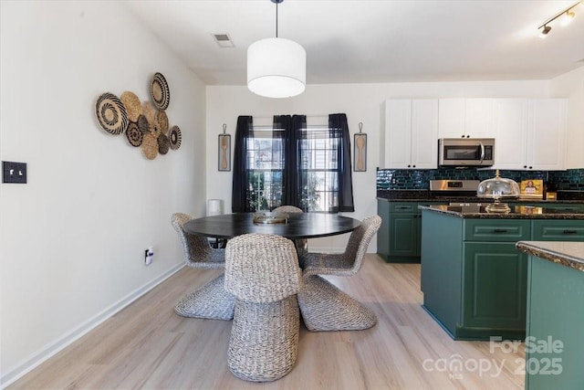 kitchen with decorative backsplash, white cabinets, visible vents, light wood finished floors, and stainless steel appliances