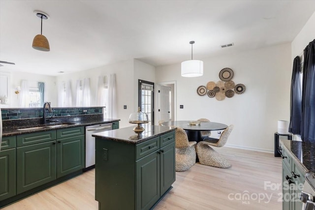 kitchen featuring visible vents, light wood finished floors, dishwasher, a sink, and green cabinetry