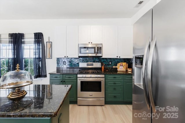 kitchen with white cabinetry, stainless steel appliances, decorative backsplash, visible vents, and green cabinetry
