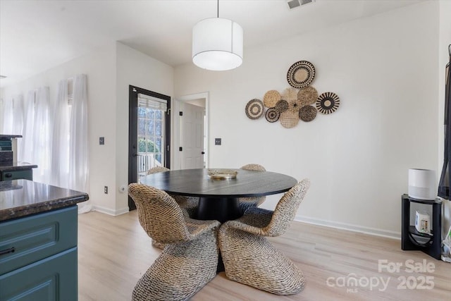 dining space with baseboards, visible vents, and light wood-style floors
