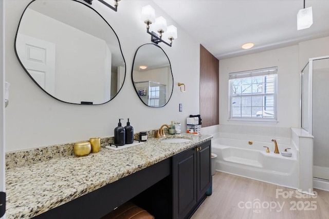 bathroom featuring wood finished floors, vanity, a bath, and a shower stall