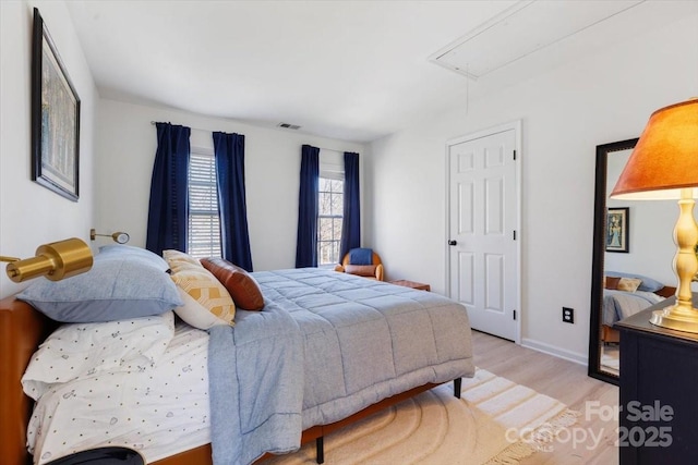 bedroom featuring attic access, baseboards, visible vents, and wood finished floors