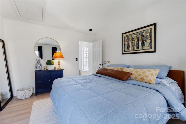 bedroom featuring light wood-style floors and attic access