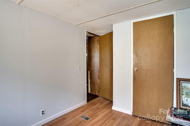 spare room with baseboards, light wood finished floors, and visible vents