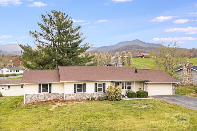 ranch-style home featuring stone siding, a front yard, a mountain view, and an attached garage