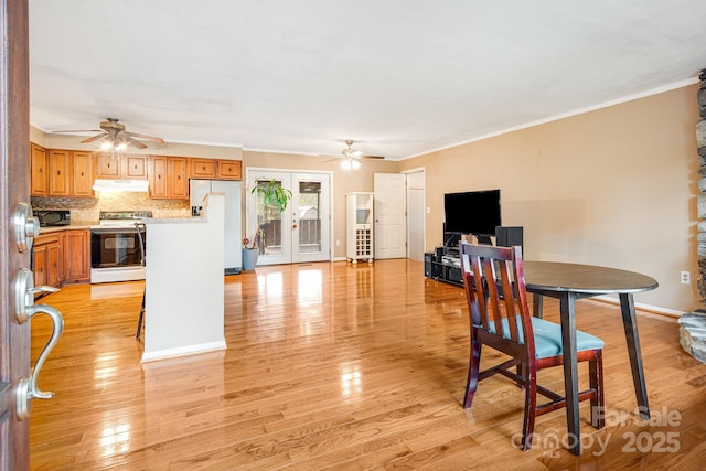 dining space featuring ceiling fan, light wood-style flooring, and crown molding