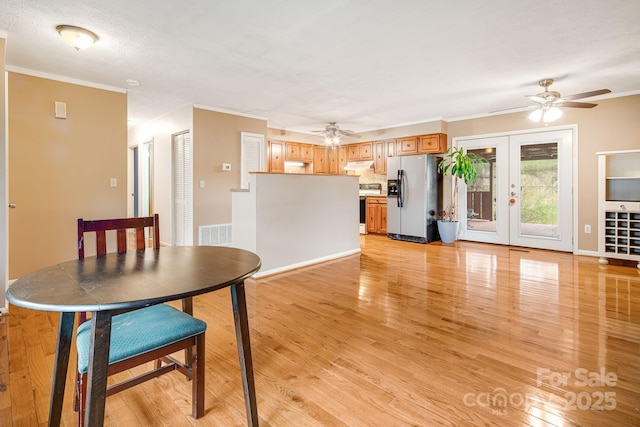 dining room with light wood-type flooring, visible vents, ornamental molding, and ceiling fan