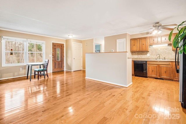 kitchen featuring light countertops, light wood-style flooring, black dishwasher, tasteful backsplash, and a sink