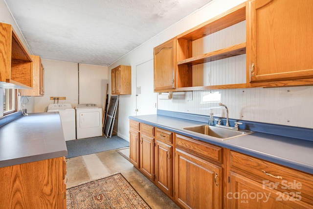 kitchen with open shelves, independent washer and dryer, a textured ceiling, a sink, and brown cabinetry