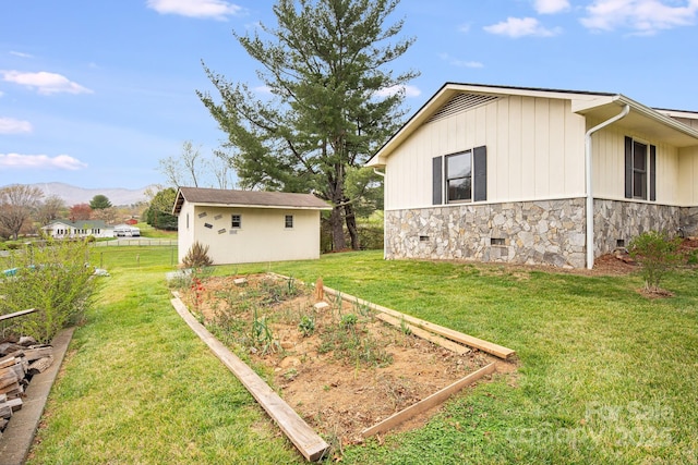 view of side of home with crawl space, a yard, an outbuilding, and a vegetable garden