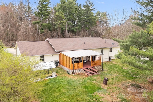 back of property featuring an exterior structure, a shingled roof, a deck, and a yard