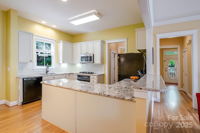 734 E 10th St, Charlotte, NC 28202 - kitchen with light wood-style flooring, black appliances, a sink, and a peninsula