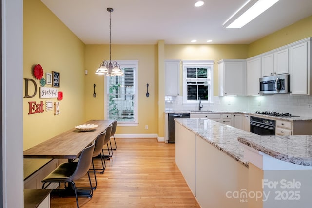 734 E 10th St, Charlotte, NC 28202 - kitchen featuring light wood-type flooring, black appliances, white cabinets, and plenty of natural light