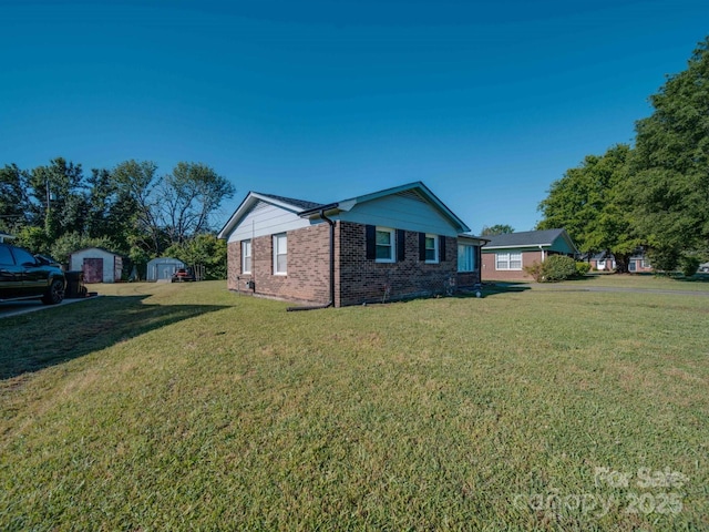 view of front of property with a storage unit, brick siding, a front lawn, and an outbuilding
