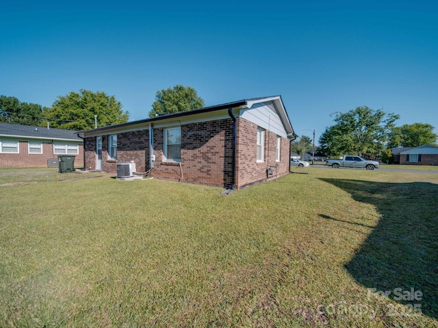 rear view of property with a yard, brick siding, and central AC